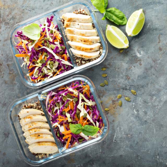 View of two meal prepped lunches or dinners with grilled chicken, salad, and rice