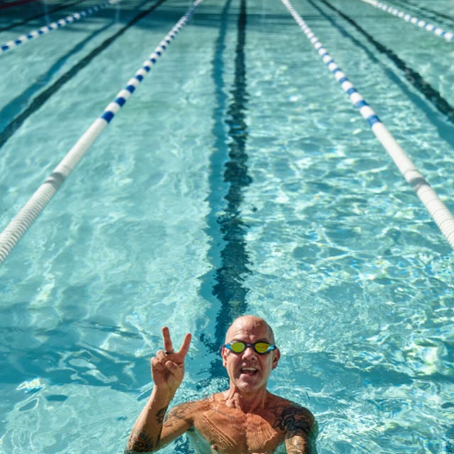 Man doing the peace sign with his fingers smiling in the lap pool