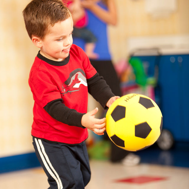 Boy aged 2 playing with a soccer ball inside Kids World