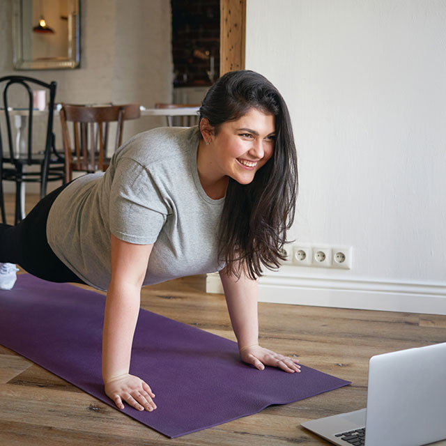 Woman in a plank doing a virtual Rev32 workout indoors