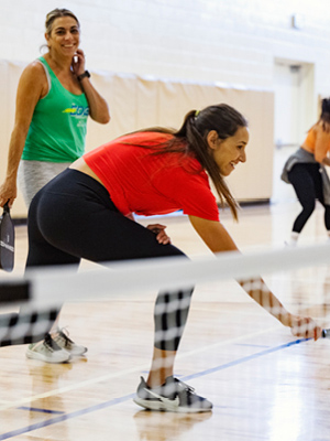 A woman diving forward to reach and hit the pickleball