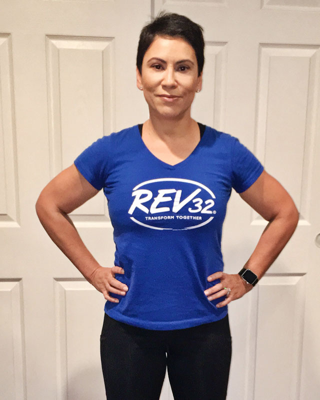 A woman standing with her hands on her hips looking proud wearing a Rev32 shirt
