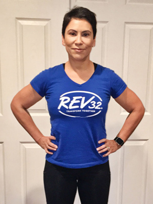 A woman standing with her hands on her hips looking proud wearing a Rev32 shirt