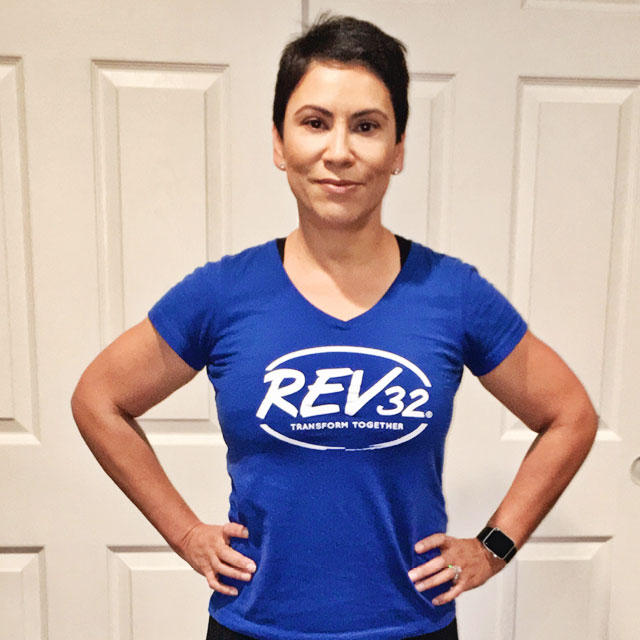 A woman standing with her hands on her hips looking proud wearing a Rev32 shirt