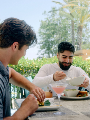 A man and woman laughing and smiling while enjoying beers on the patio of Citrus Fresh Grill