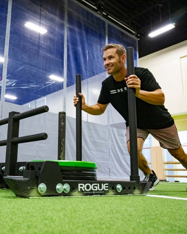 A man pushing a weighted sled in The Edge Performance Training space