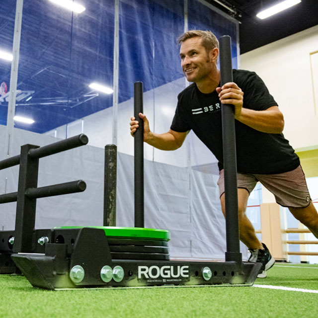 A man pushing a weighted sled in The Edge Performance Training space