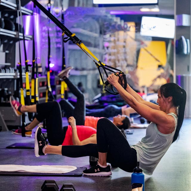 Woman doing an exercise on a TRX during a Formula3 Forge Circuit boutique fitness class