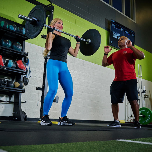 Woman lifting a weighted barbell during a personal training session