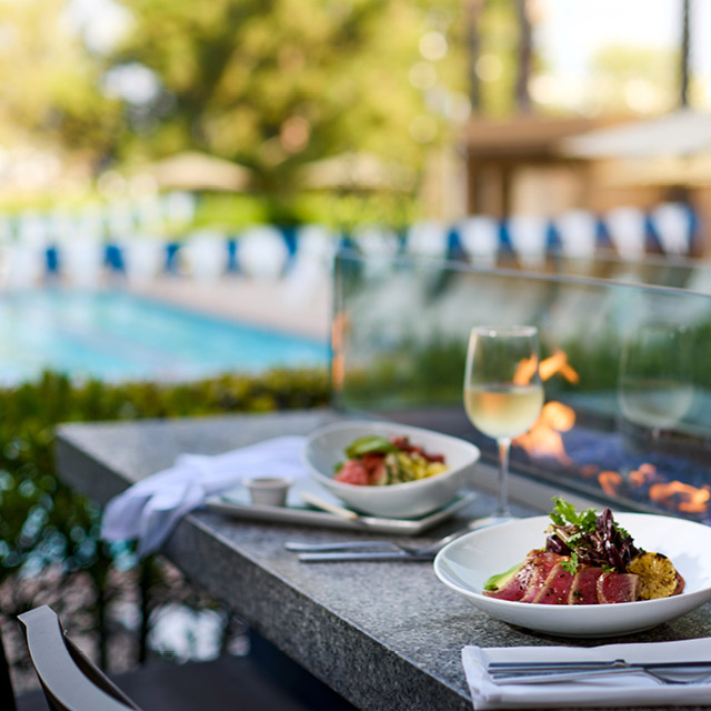 Delicious food set next to the large fire table on the outdoor Citrus Fresh Grill patio