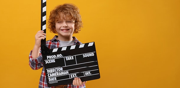 A 5-year-old boy holding a director's sign