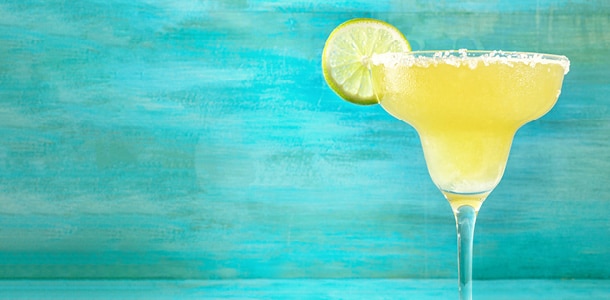 A blended margarita with lime in a large margarita glass