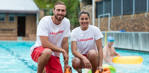 Two lifeguards next to a pool in their uniforms