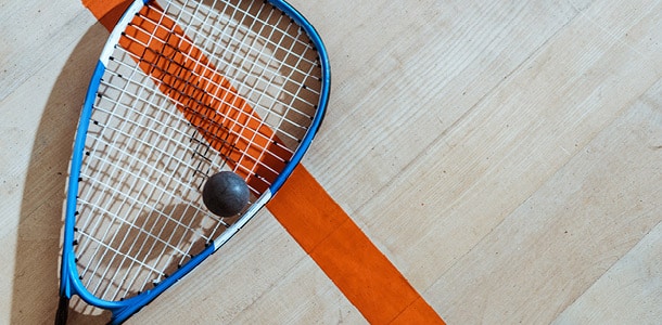 A squash racquet and ball on the floor of a squash court