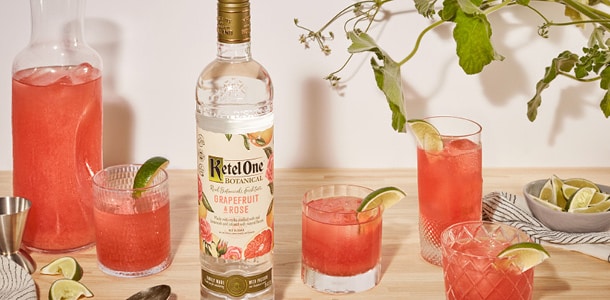 Ketel One vodka bottle with pink cocktails garnished with lime