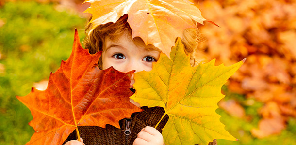 A child playing with fall leaves at Parents' Escape