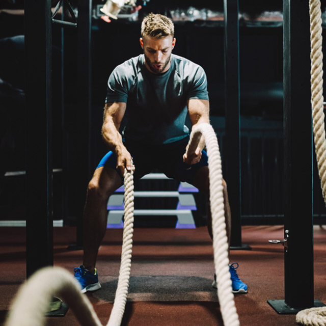 A man working out at ClubSport using battleropes