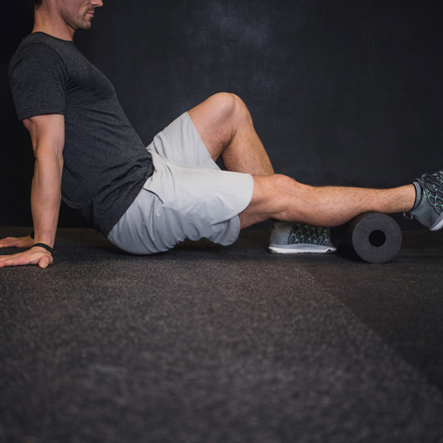 A man using a foam roller amenity as a muscle recovery method