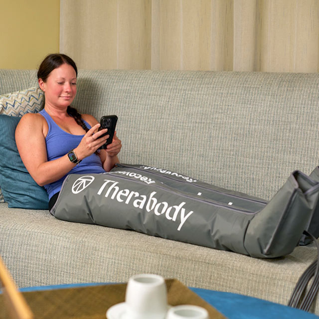 A woman using the Therabody RecoveryAir Compression boots for muscle recovery