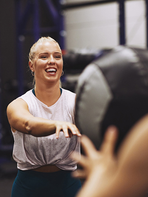 A woman in an RGT Rev Group Training class exercising with a weighted ball